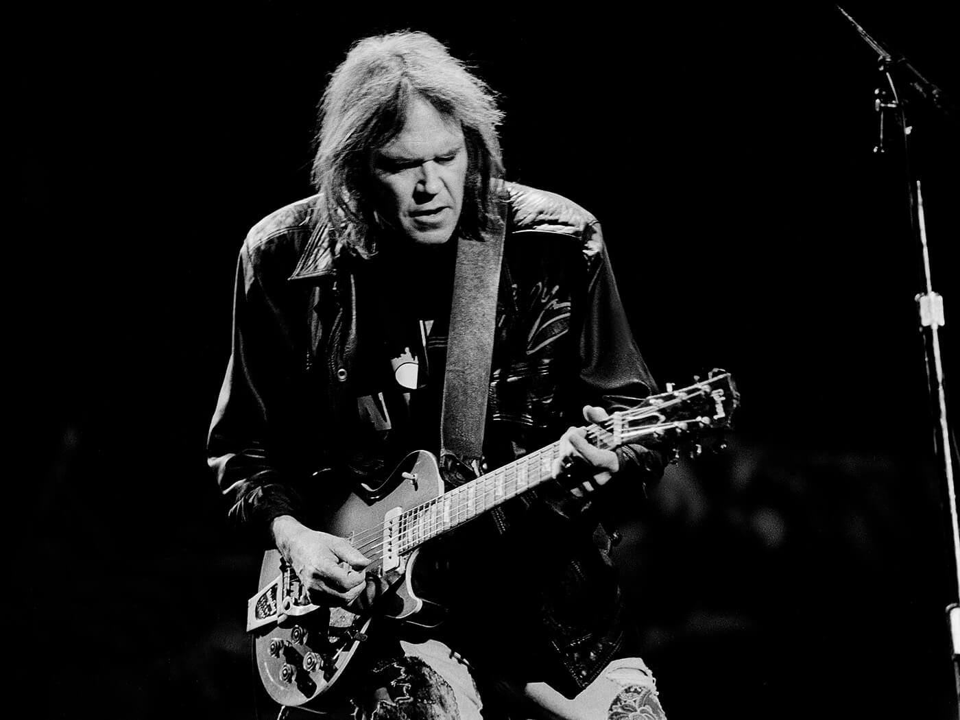 Neil Young plays guitar as he performs onstage during the Farm Aid benefit concert, Indianapolis, Indiana, April 7, 1990
