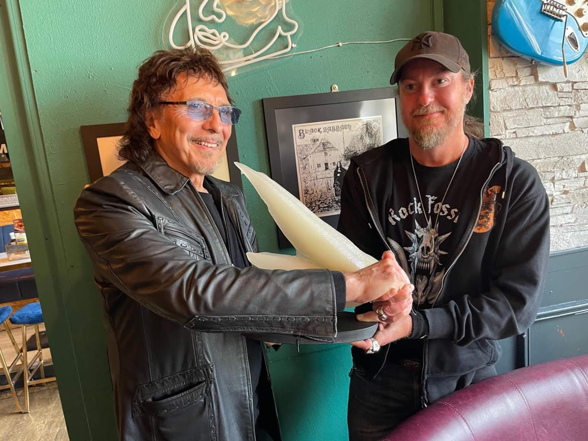 Tony Iommi holds a sculpture of a fossil named after him