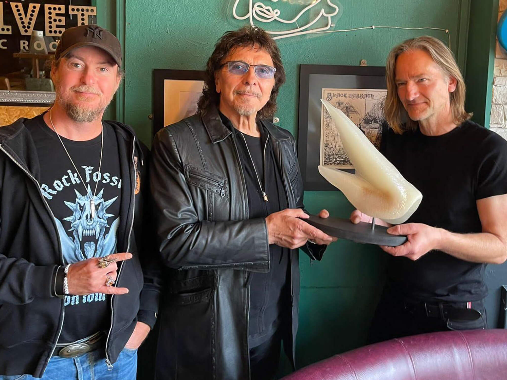 Tony Iommi holds a sculpture of a fossil named after him