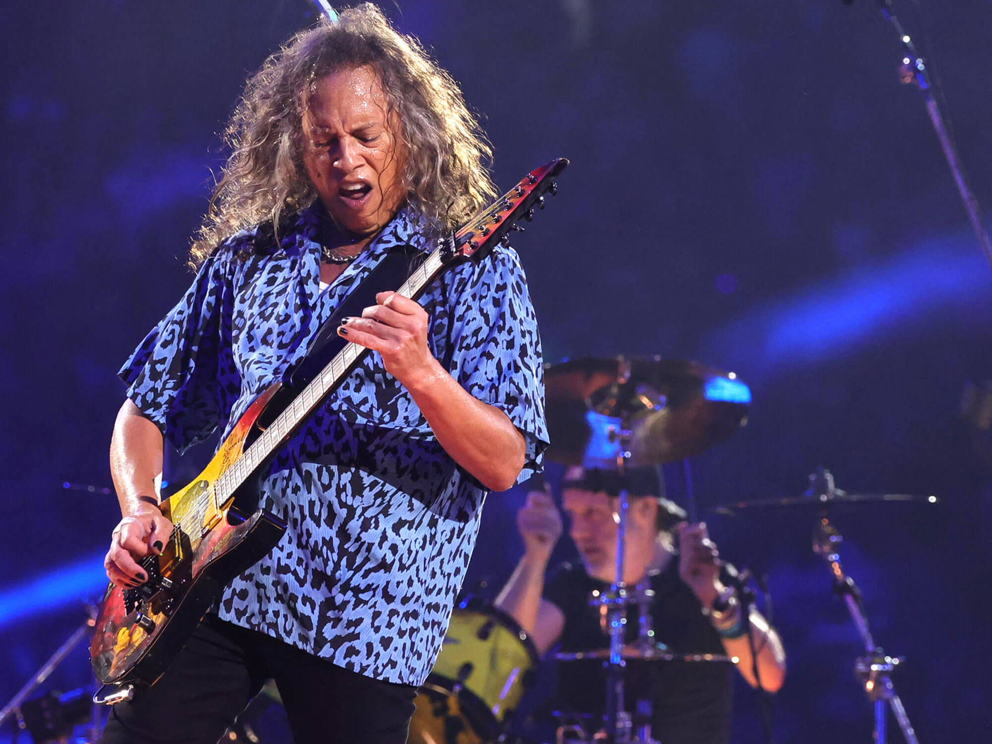 Kirk Hammett performing onstage with Lars Ulrich in the background