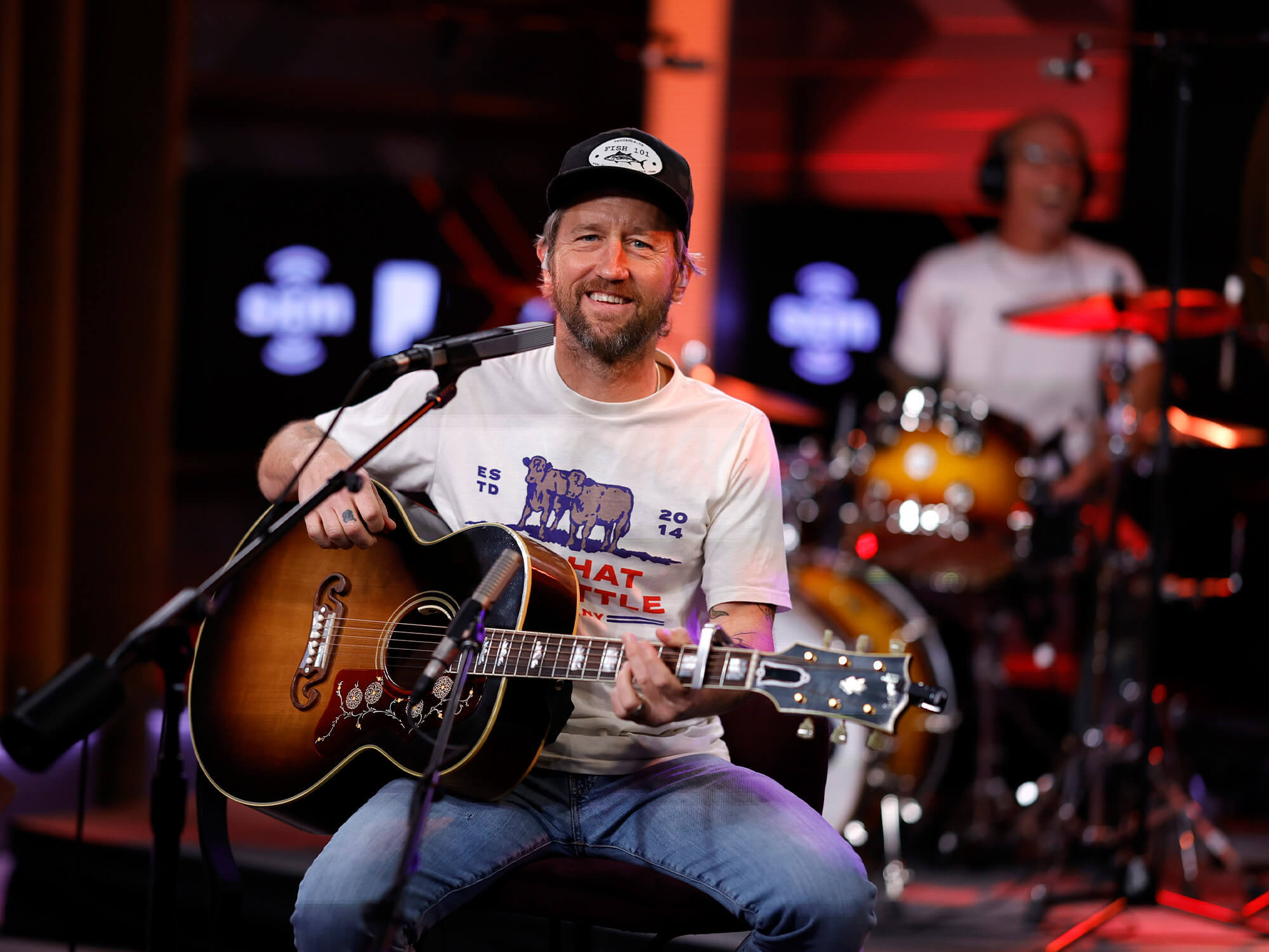 Chris Shiflett smiling and holding an acoustic Gibson guitar