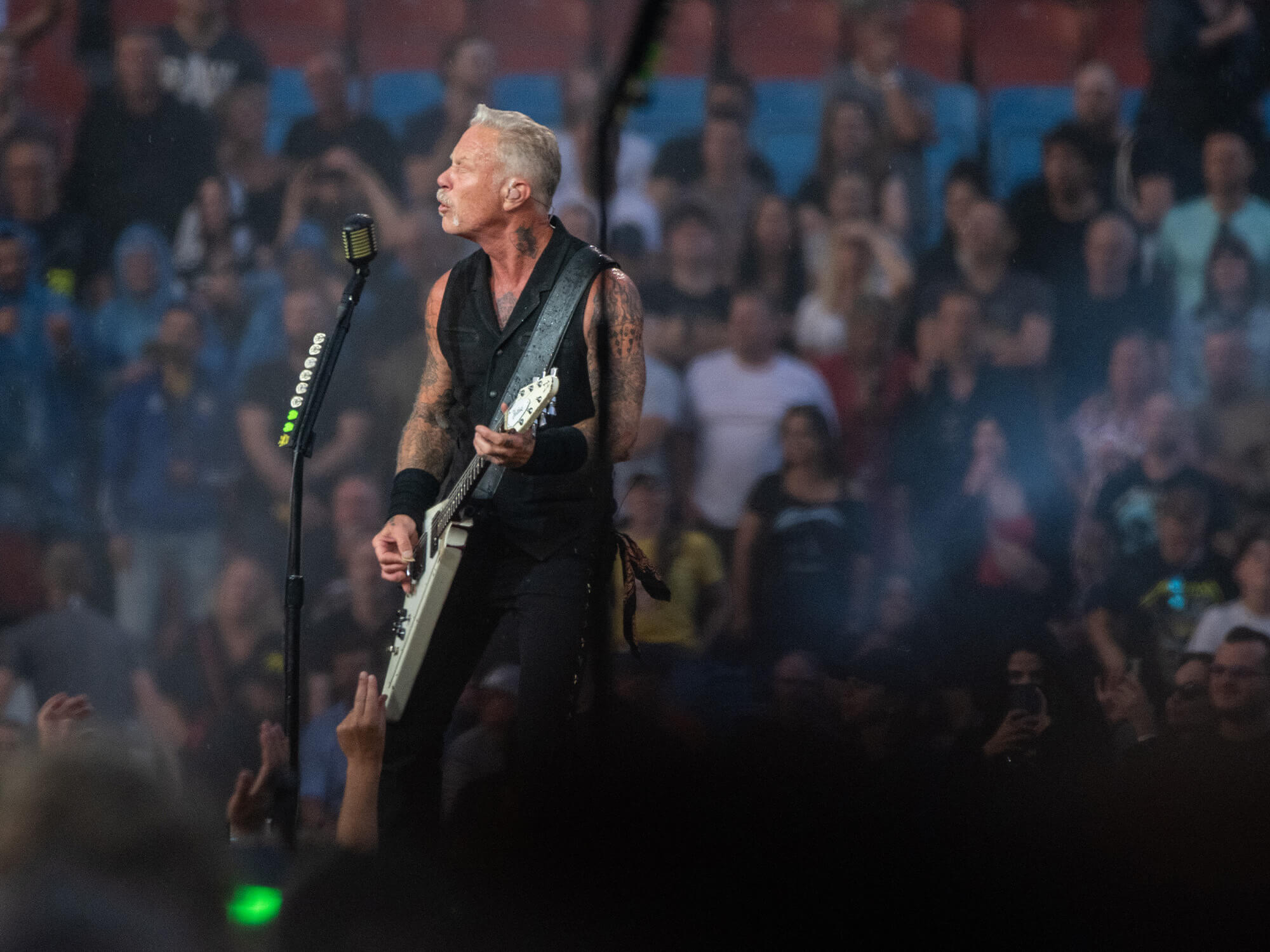James Hetfield of Metallica playing his Gibson Flying V with a blurred crowd behind him