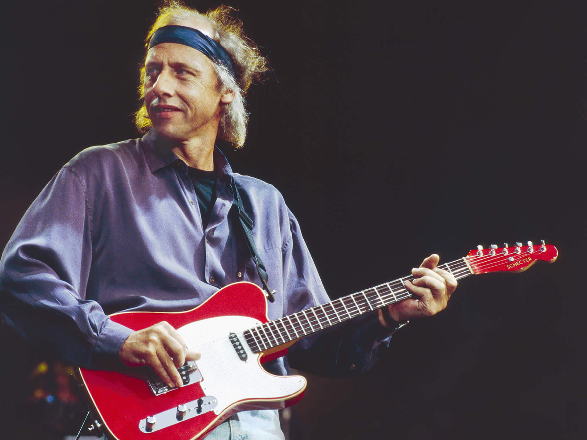 Mark Knopfler of Dire Straits playing a Schecter guitar in 1991 by Phil Dent/Redferns via Getty Images