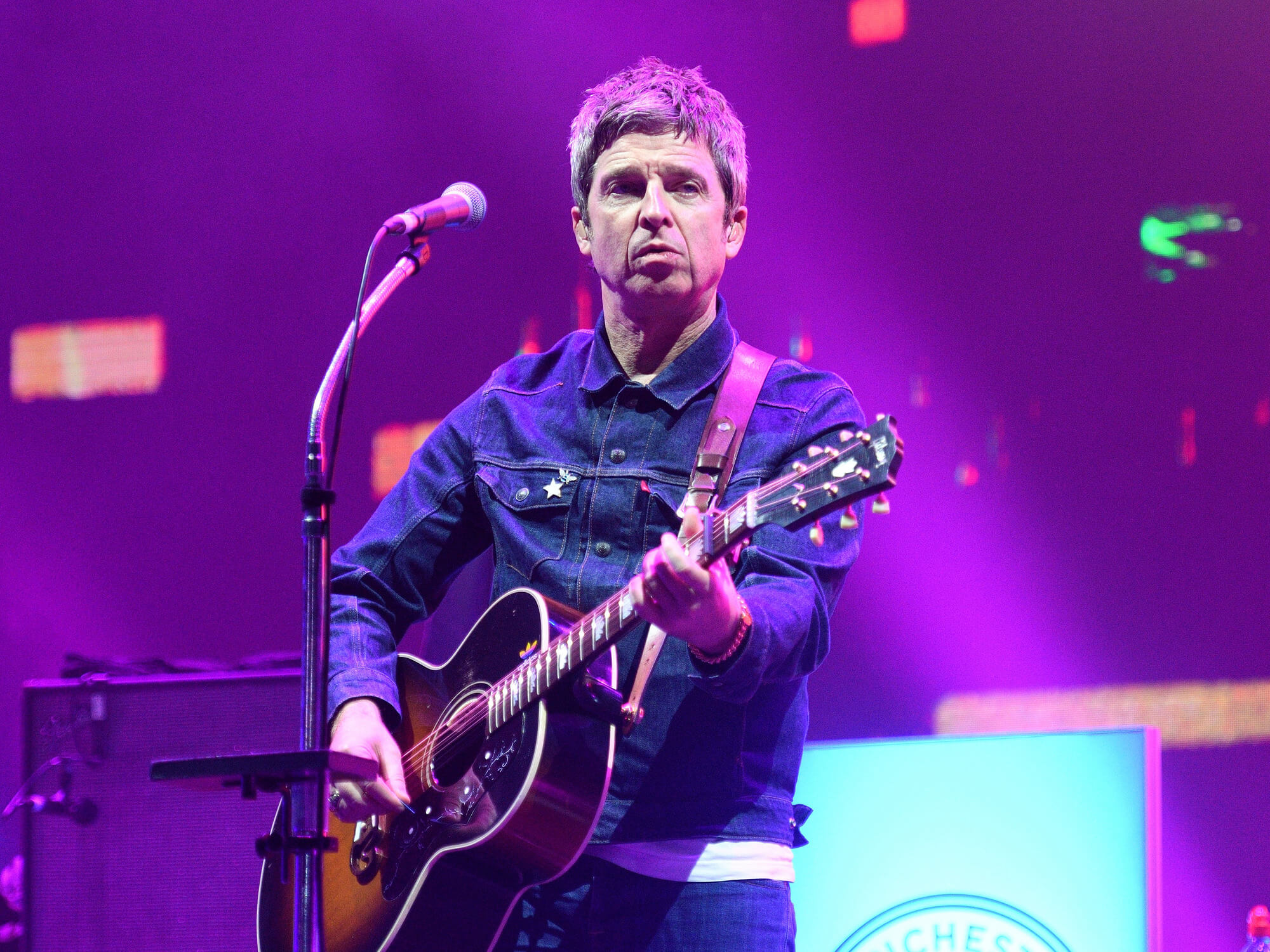 Noel Gallagher playing guitar on stage