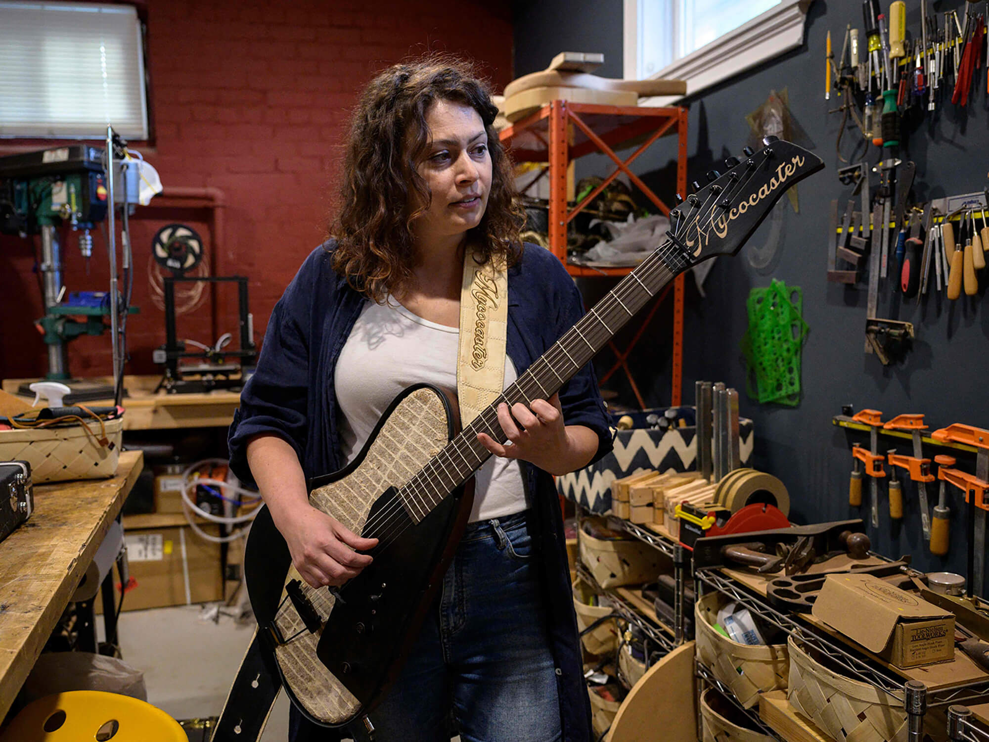 Rachel Rosenkrantz holding up her “Mycocaster”, a mycelium and paper guitar