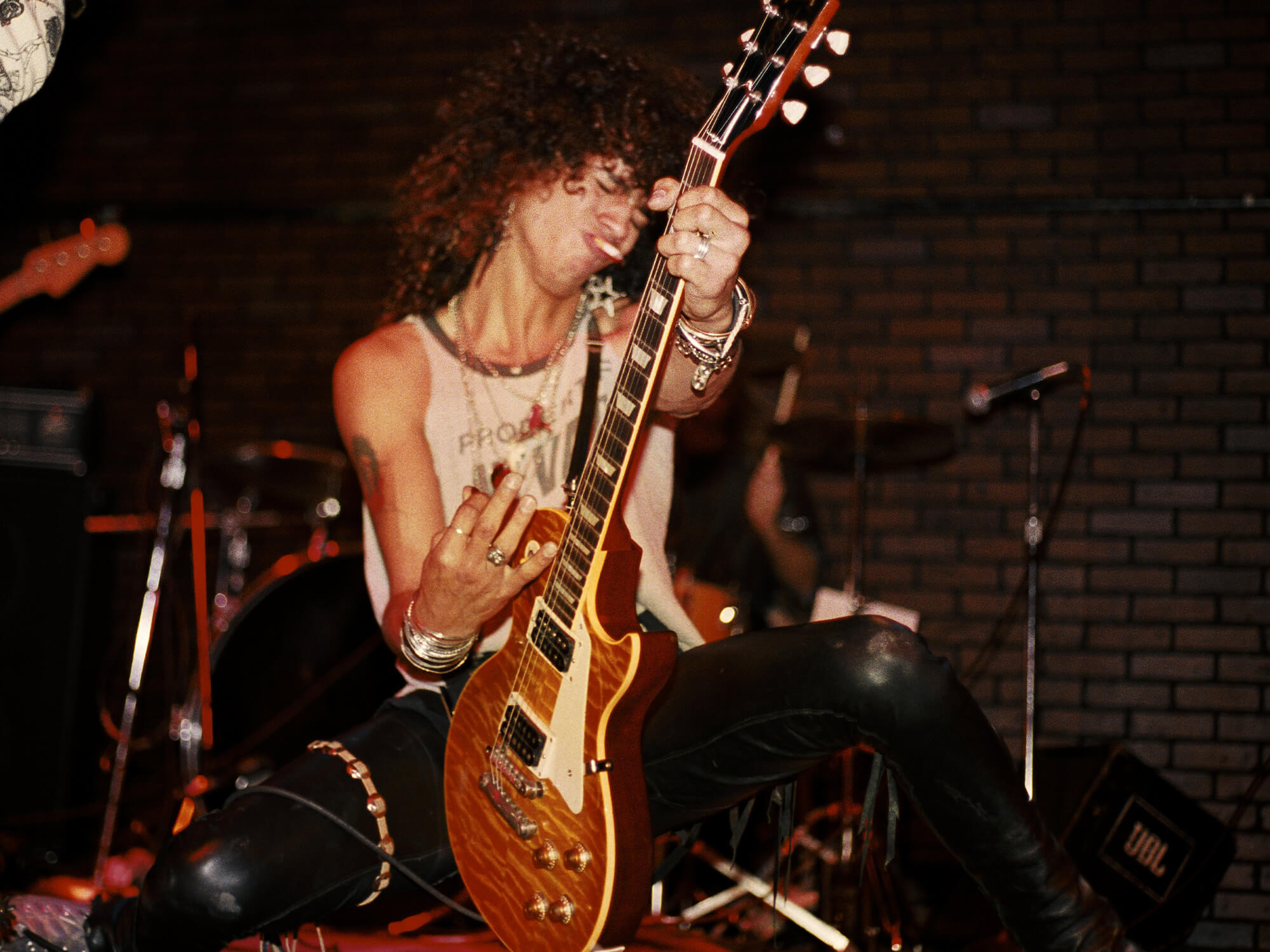 Slash in 1985, he has a cigarette in his mouth and is playing guitar