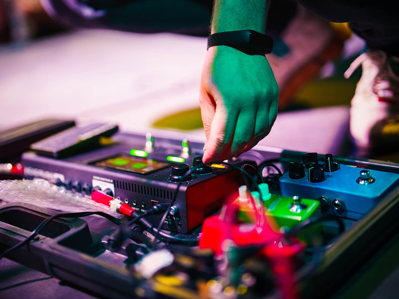 Musician adjusting guitar pedals on stage, photo by Ugur Karokac/Getty Images