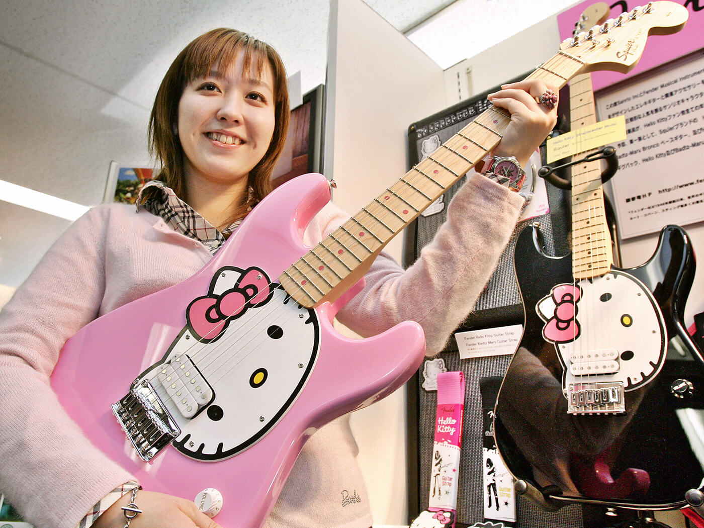 Sanrio employee holding up a “Hello Kitty Stratocaster” produced by Squier in 2006 by Yoshikazu Tsuno/AFP via Getty Images