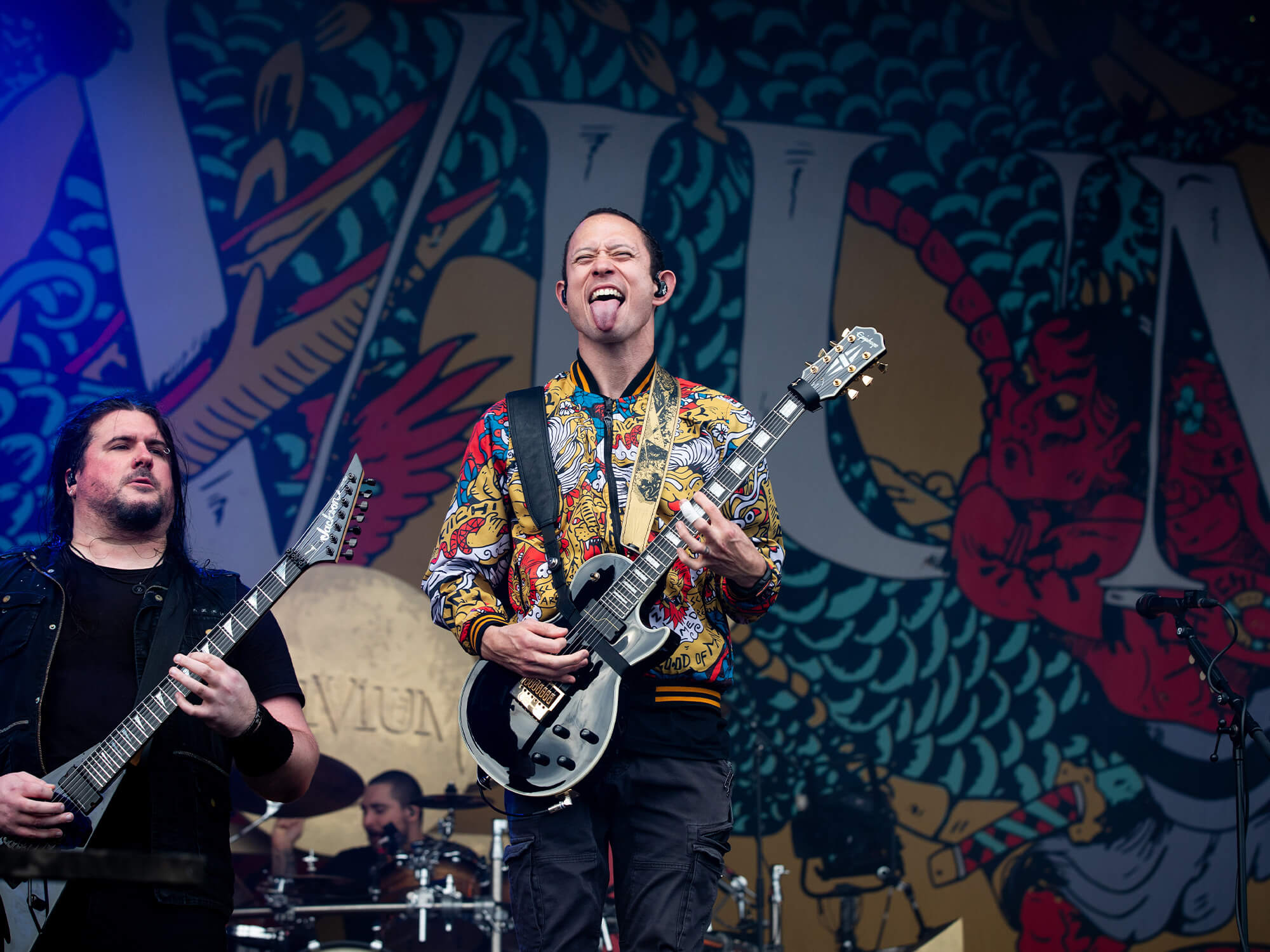 Matt Heafy on stage in 2023, he's playing guitar and sticking his tongue out at the crowd.