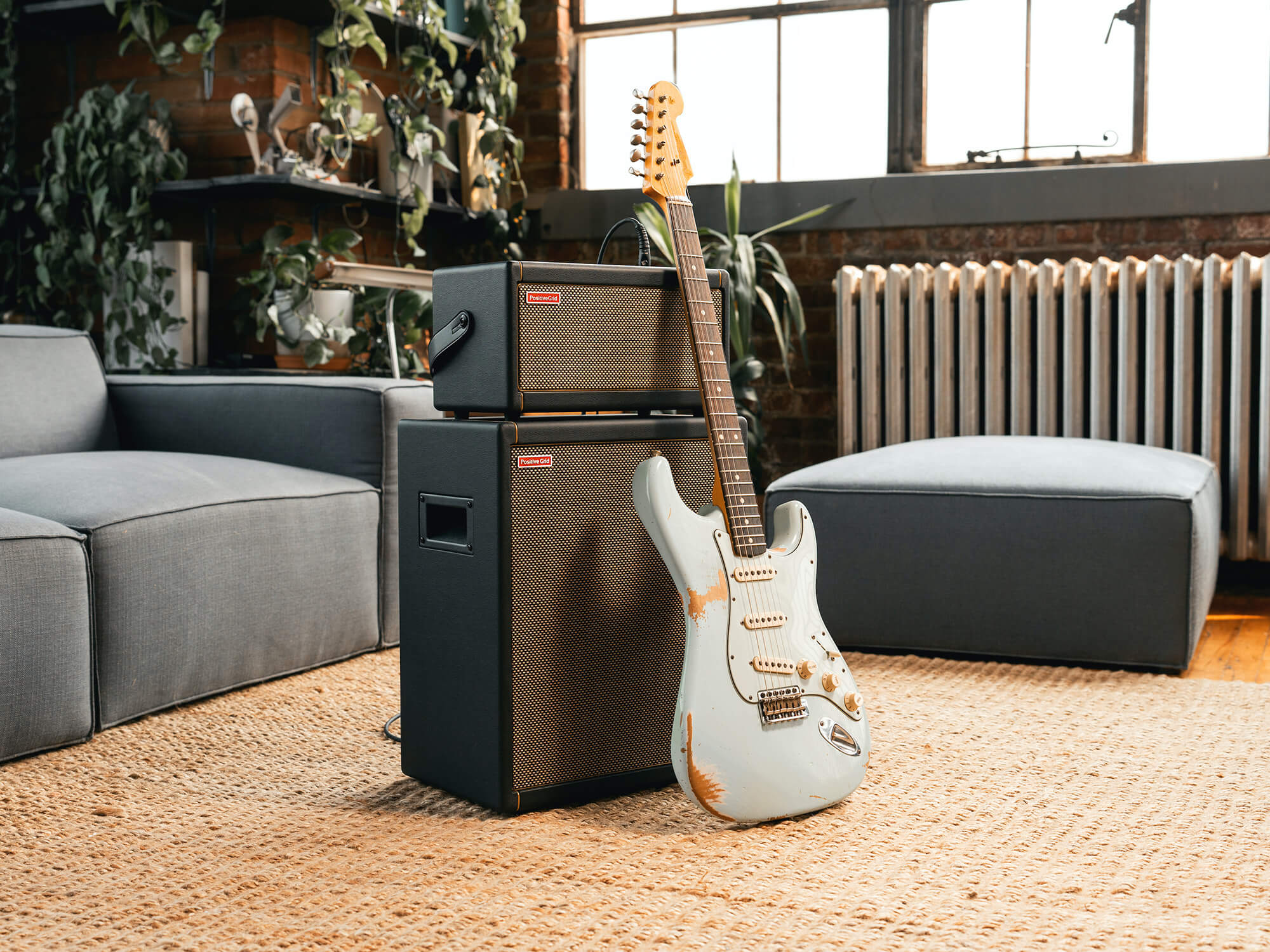 Positive Grid Spark CAB in a home environment, with a white Strat guitar leaning against it. It has a black outer shell and a brown grille.