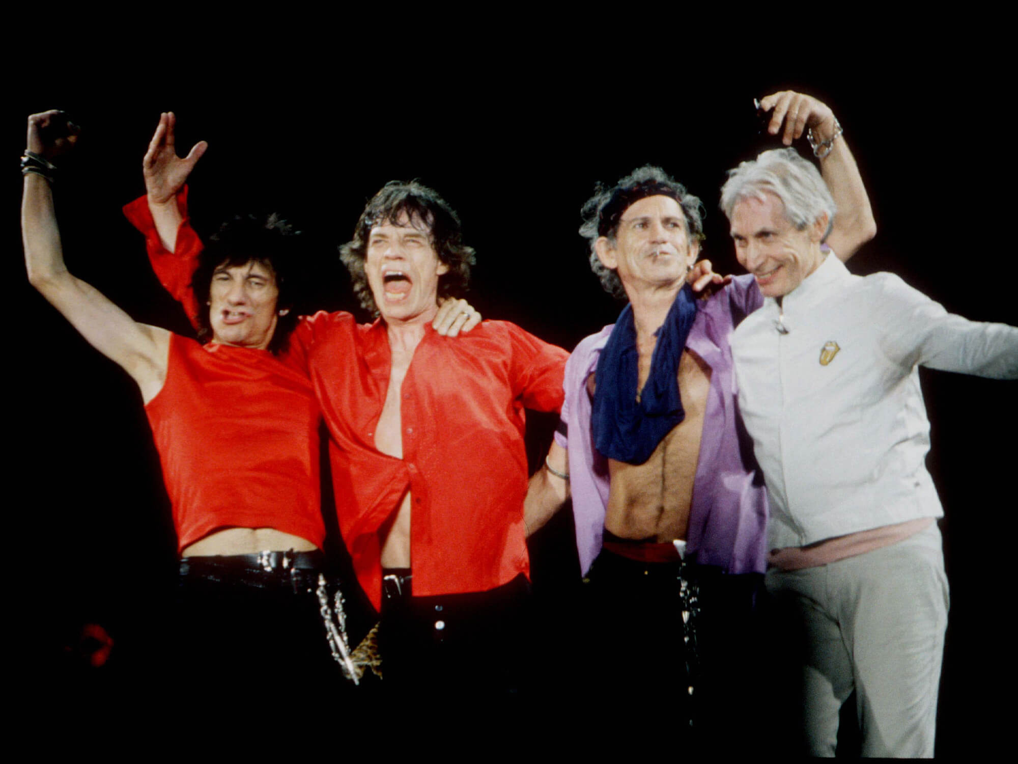 The Rolling Stones with their arms around each other on stage in 1998.