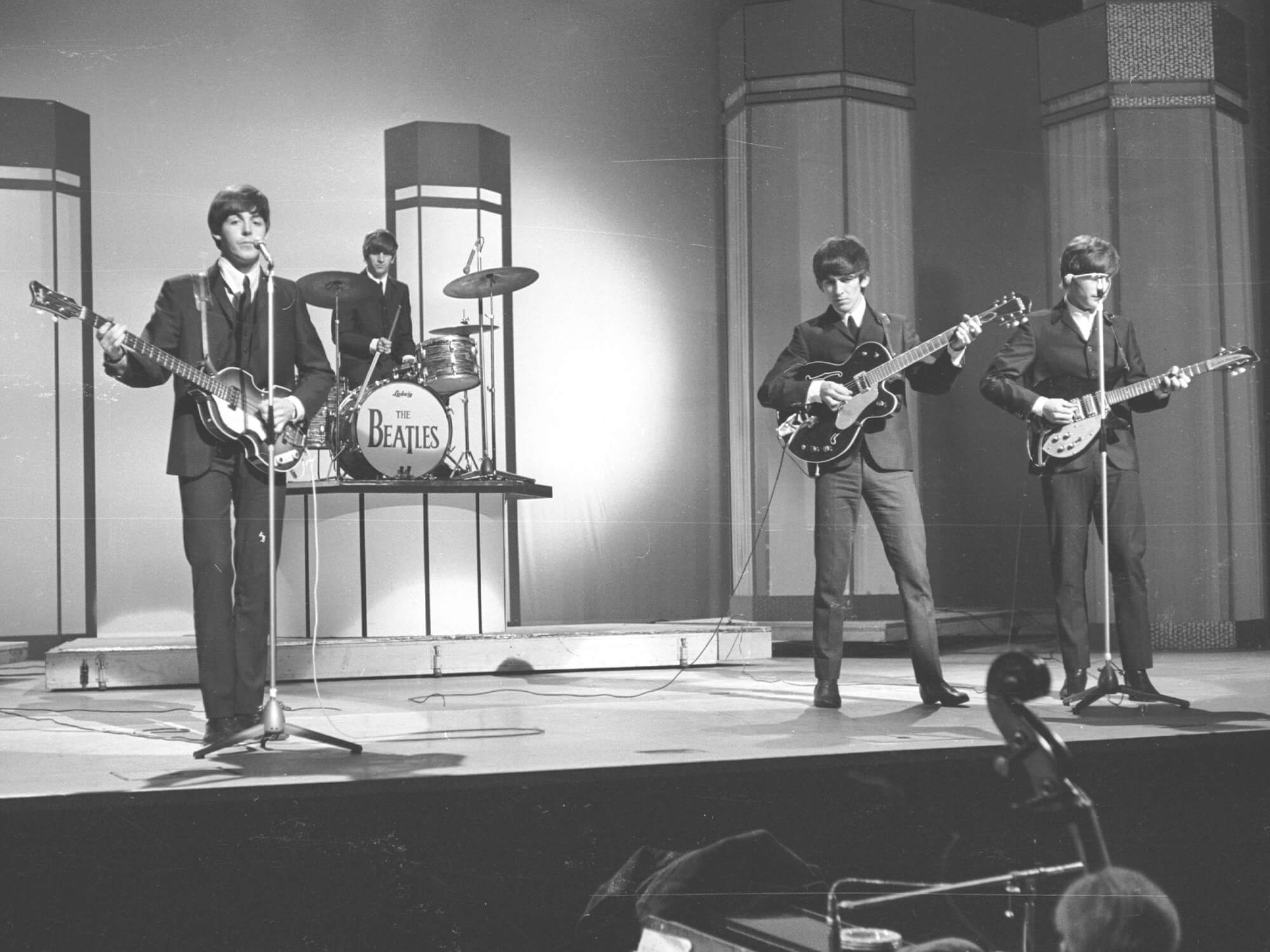 Black and white archival photo of The Beatles on stage.