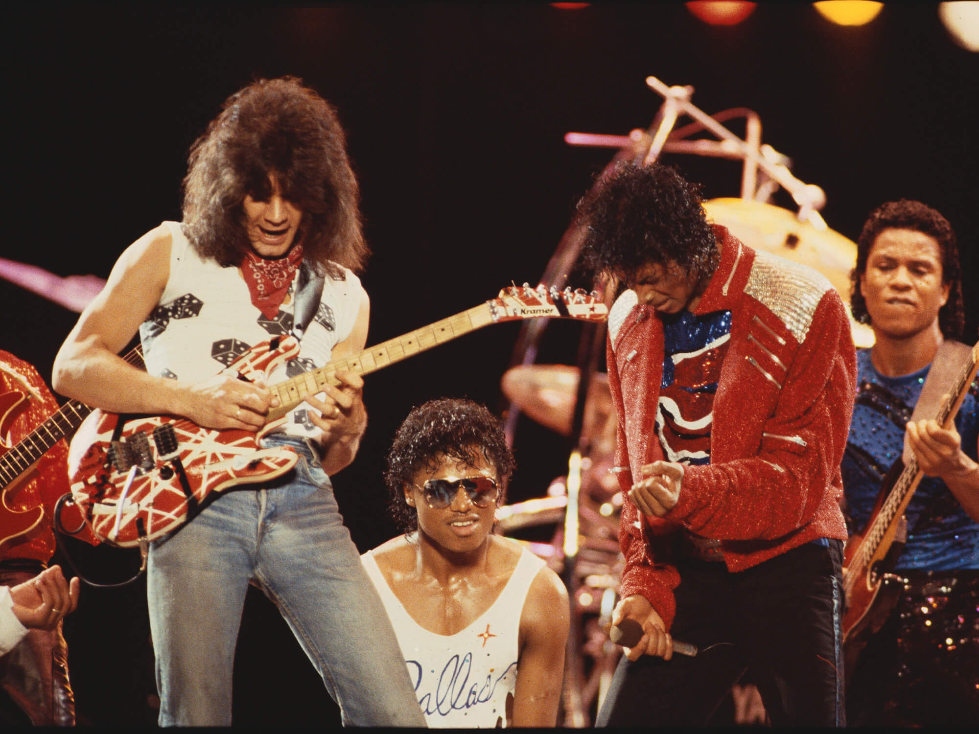 Eddie Van Halen and Michael Jackson on stage together. Eddie is playing his famous frankenstrat, with Jackson doing air guitar gestures with his hands next to him.