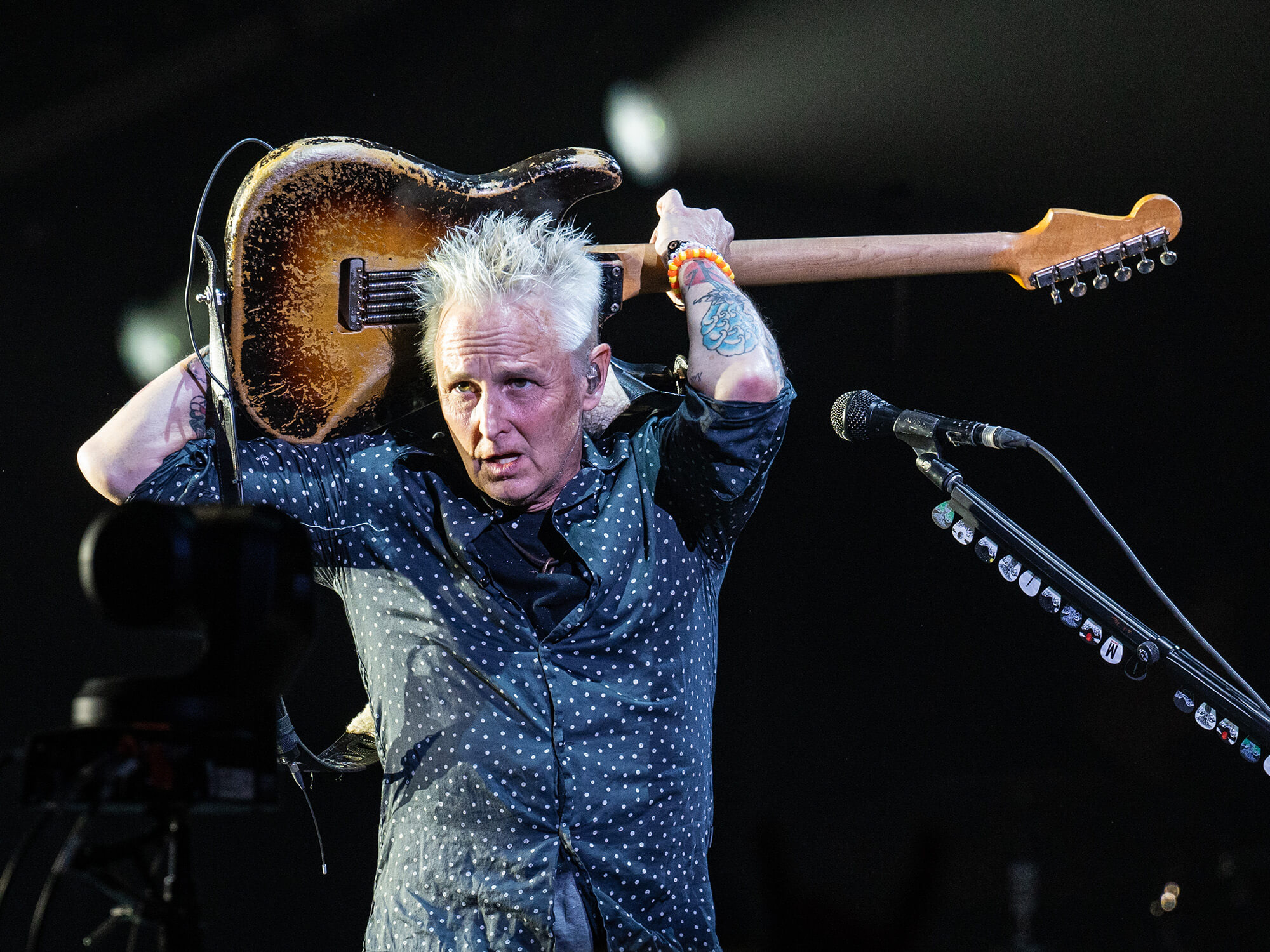 Mike McCready holding his guitar behind his head and playing it whilst on stage.