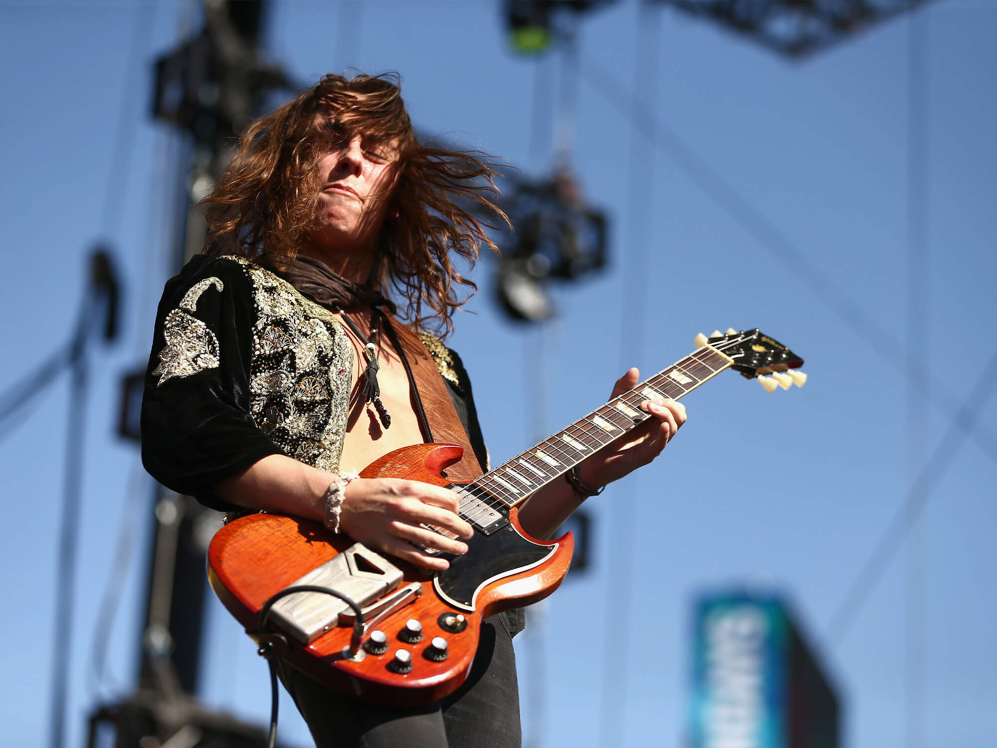 Jake Kiszka on stage. He is playing guitar and his hair is swished to the side.