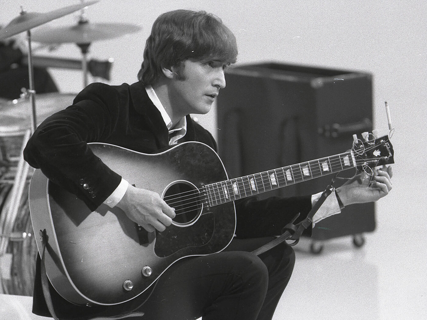 John Lennon tuning his Gibson J-160E during the filming of ‘A Hard Day’s Night’, photo by Max Scheler - K & K/Redferns via Getty Image