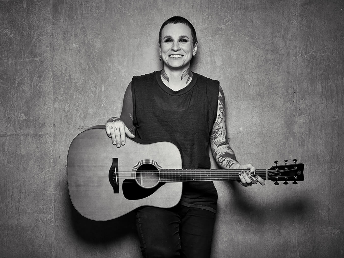Black and white photo of Laura Jane Grace with a Yamaha acoustic guitar, photo by Travis Shinn