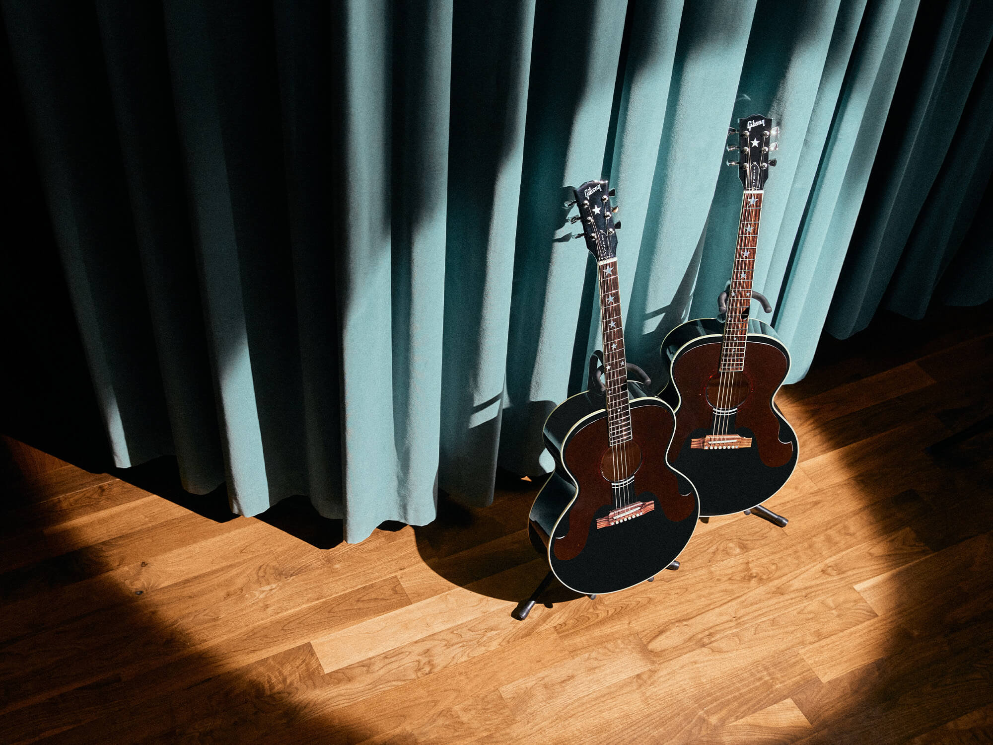 Two of The Everly Brothers J-180 acoustics photographed together under a spotlight