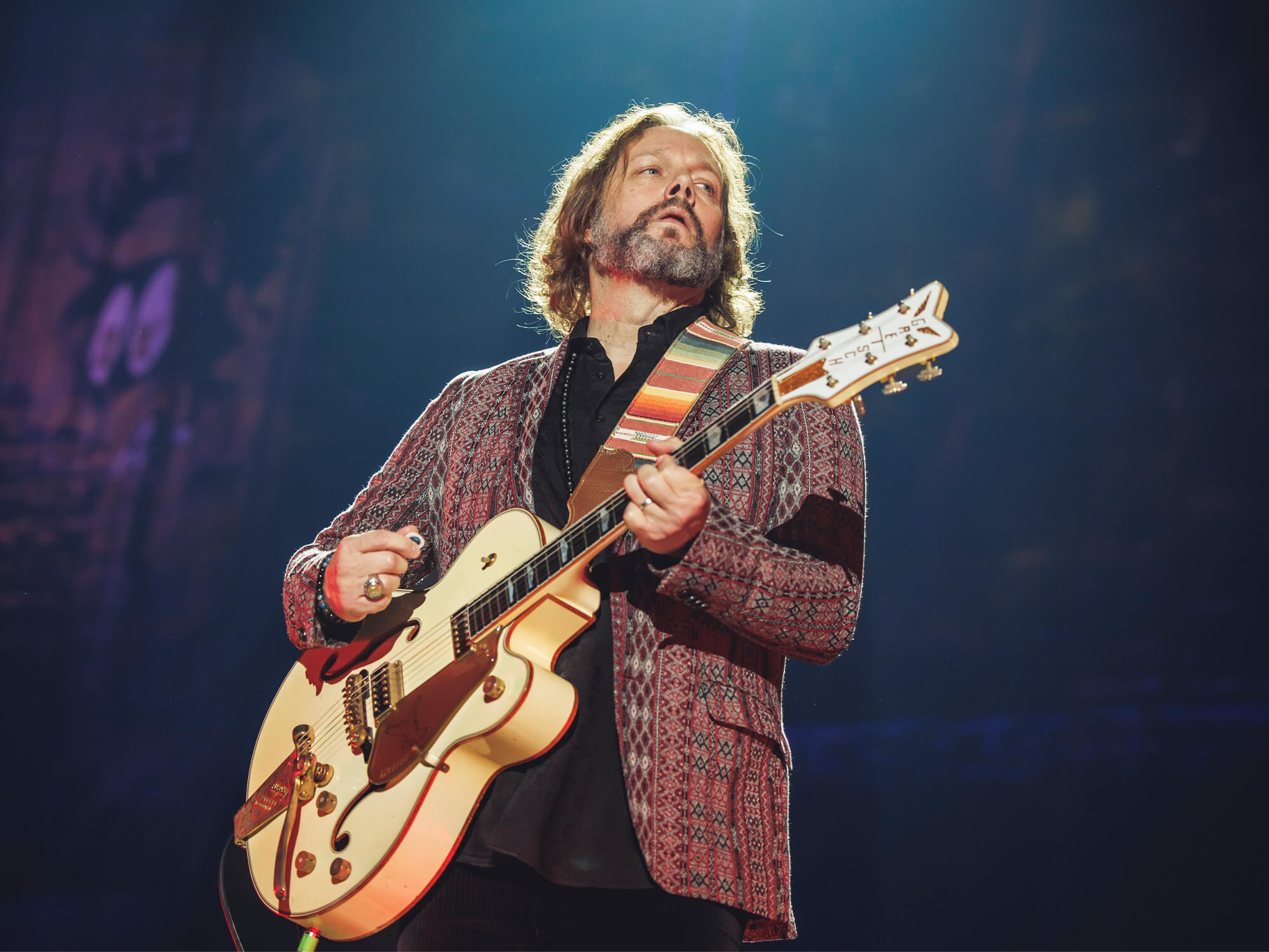 Rich Robinson playing a Gretsch guitar on stage.