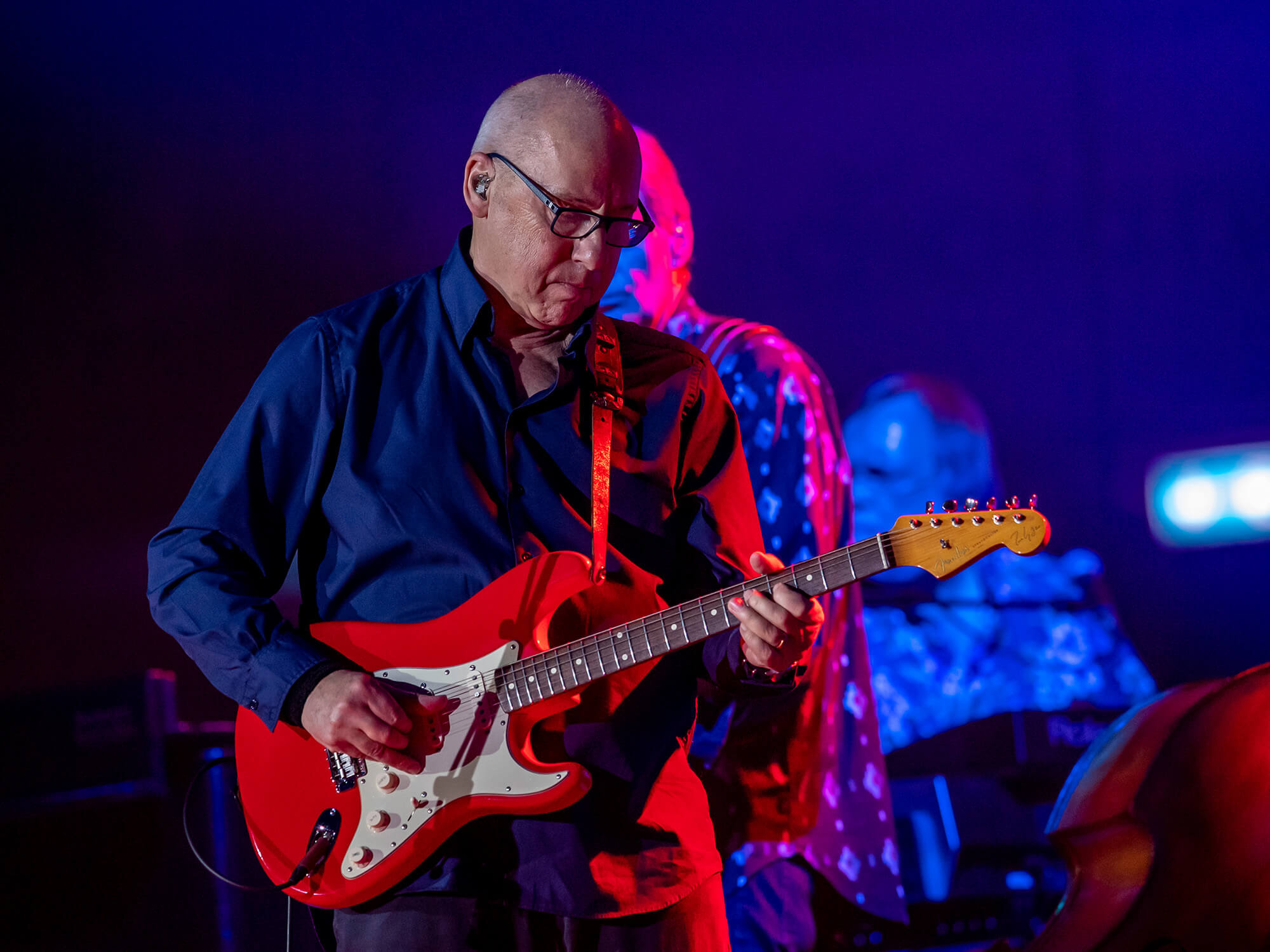 Mark Knopfler on stage playing a red Stratocaster