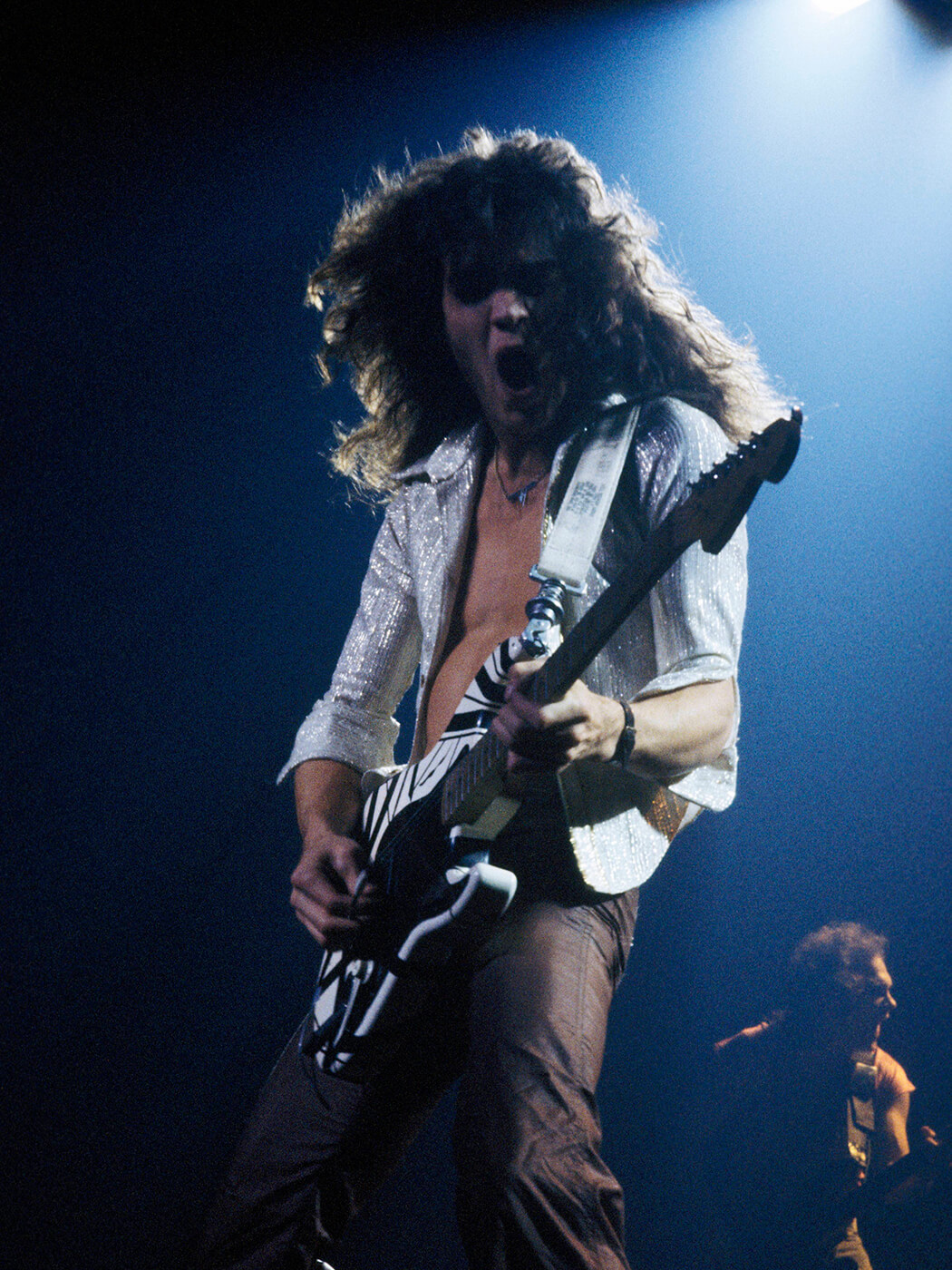 Eddie Van Halen performing onstage with his Frankenstein guitar in 1978. It sports black and white stripes. Photo by Fin Costello/Redferns via Getty Images