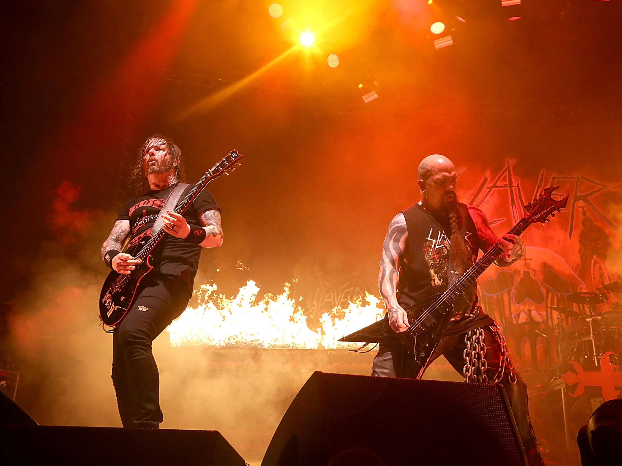 Gary Holt and Kerry King on stage in 2018. There are flames behind them.