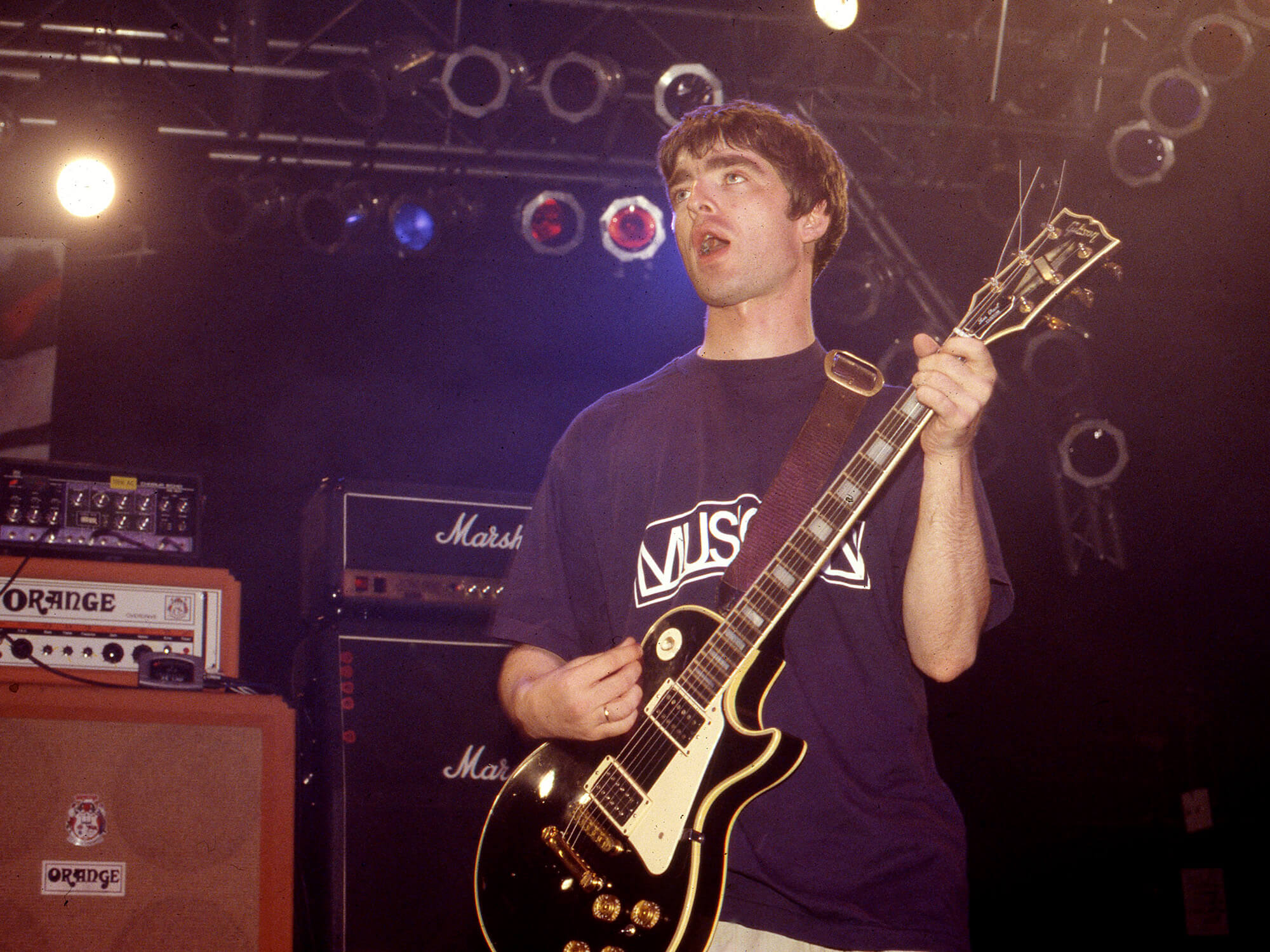 Noel Gallagher photographed on stage in 1994 with his guitar