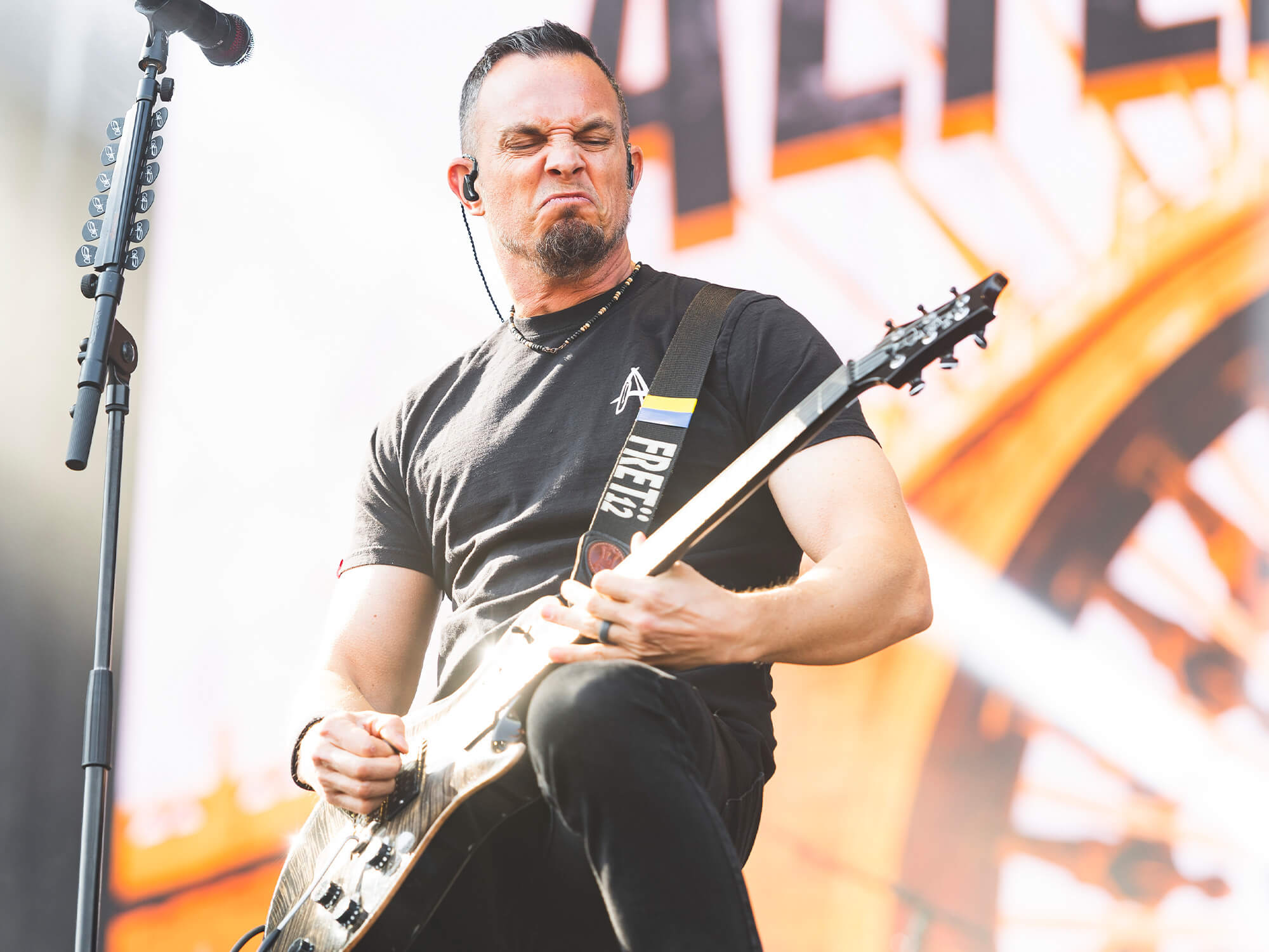 Mark Tremonti playing guitar on stage with a snarling expression on his face.